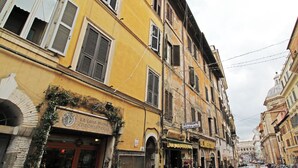 Eine enge Straße mit gelben Gebäuden, einem Restaurant namens "La Luna Nuova Erboristeria" und einem Schild für "Ristorante Mother India".