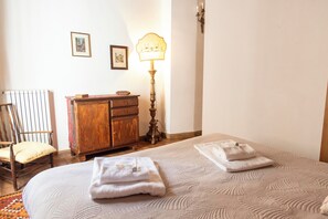 A neatly made bed with two towels, a wooden chair, a wooden dresser, and a wall-mounted lamp. - Jacopo Monti - 2 bedrooms with ansuite bathrooms (Roma)