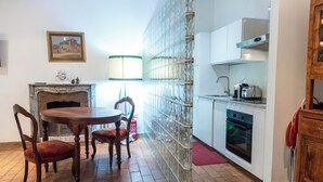 Eine Küche mit Esstisch, Stühlen, Kamin, einer Wand aus Glasbausteinen und einem Herd.