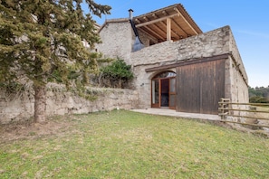 Un edificio de piedra con puerta de madera y chimenea.