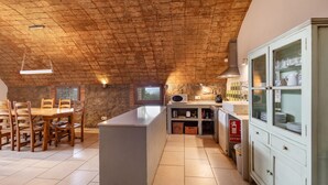 A kitchen with a brick ceiling, wooden dining table, and cabinets.