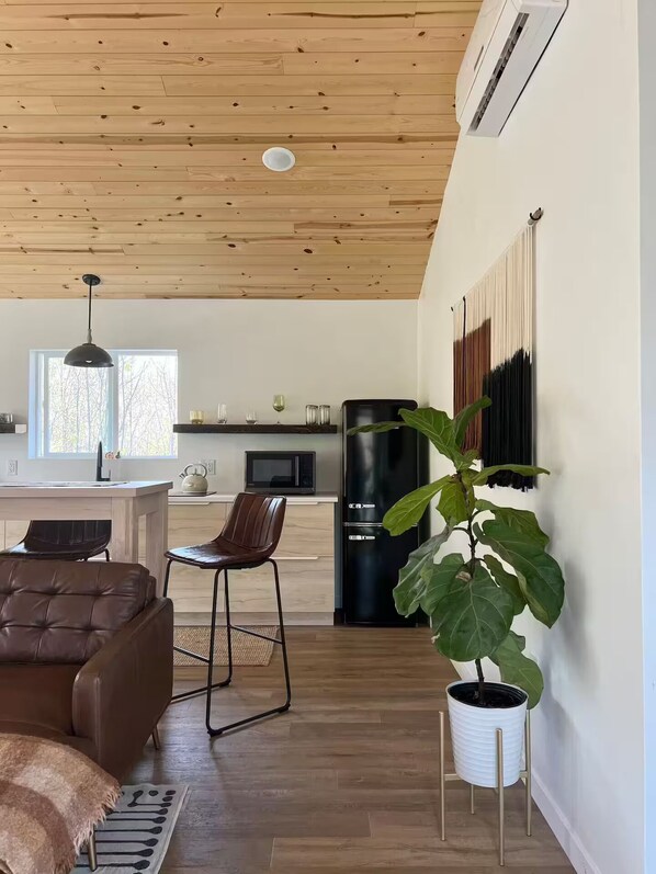 Una cocina moderna con un refrigerador negro, un microondas y una tetera sobre la encimera.