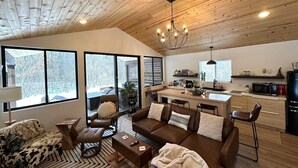Amplia sala de estar con un gran ventanal, una chimenea acogedora y una cocina moderna con microondas y refrigerador.