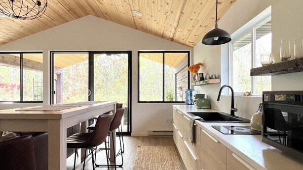 Una cocina moderna con techo de madera, ventanas amplias y una isla central con taburetes de bar.