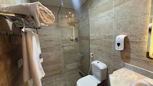 A modern bathroom with a glass-enclosed shower, a toilet, and a hand sanitizer dispenser.