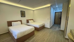 A hotel room with two beds, a wooden floor, and a framed picture on the wall.