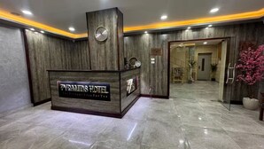 A reception desk with a clock, a sign reading "PYRAMIDS HOTEL," and a glass door leading to a hallway. - Sands of Majesty (Al Haram)
