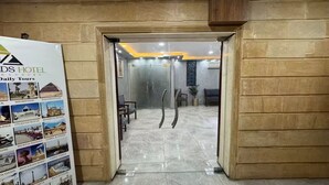 A hotel lobby with a marble floor, a reception desk, and a glass partition. - Sands of Majesty (Al Haram)