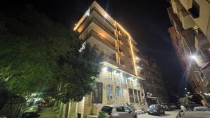 Un edificio de varios pisos con balcones, una escalera y un estacionamiento.