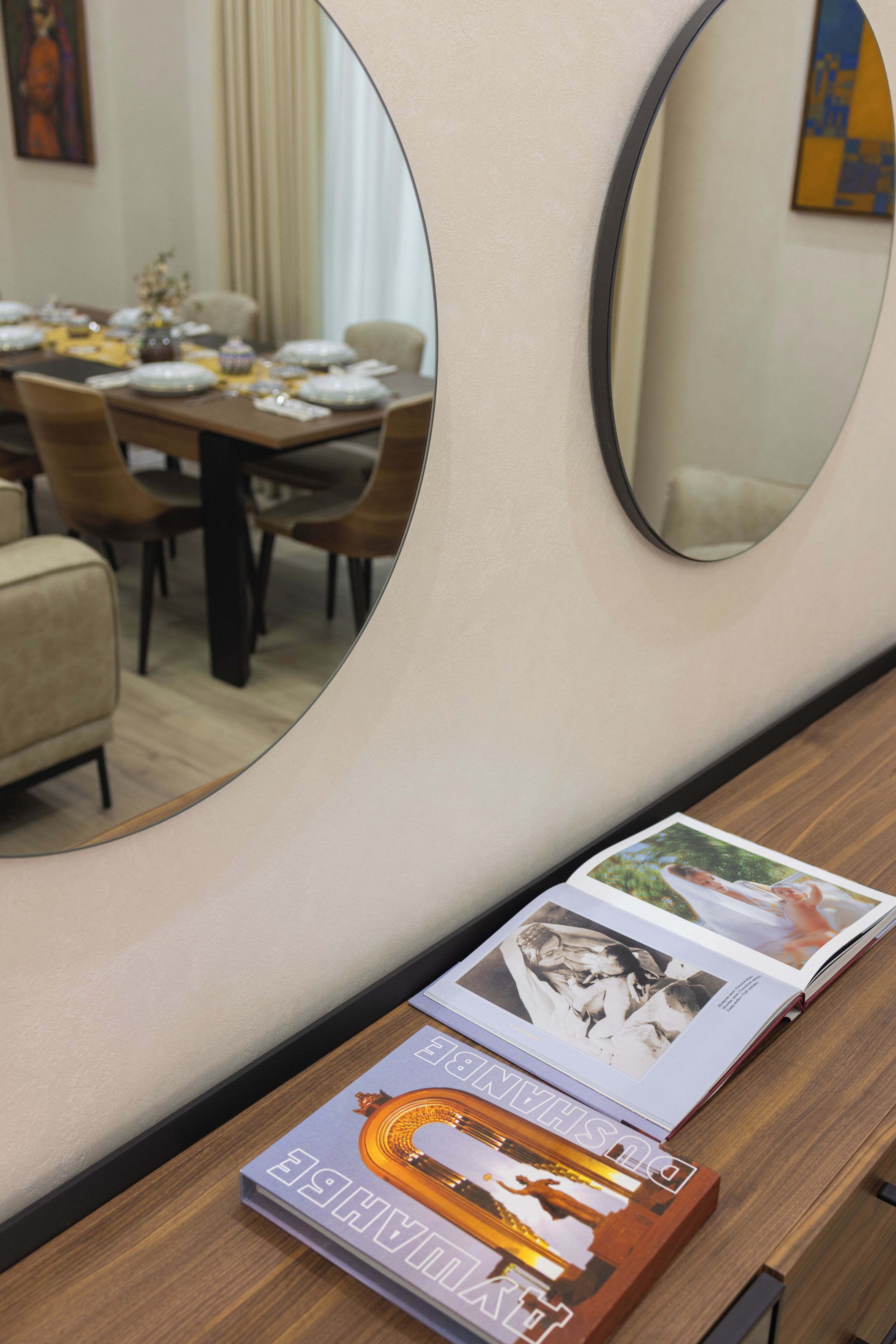 A dining area with a wooden table set for four, a mirror, and a magazine on the table.