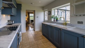 A modern kitchen with dark blue cabinets, a white countertop, and a large window.