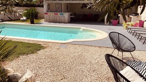 A swimming pool with a patio area, outdoor seating, and a building with a tiled roof. - Quiet villa in charming Provence village (Mouriès)