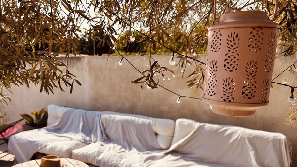 A covered outdoor seating area with a sofa, a round wooden table, and a hanging lantern. - Quiet villa in charming Provence village (Mouriès)