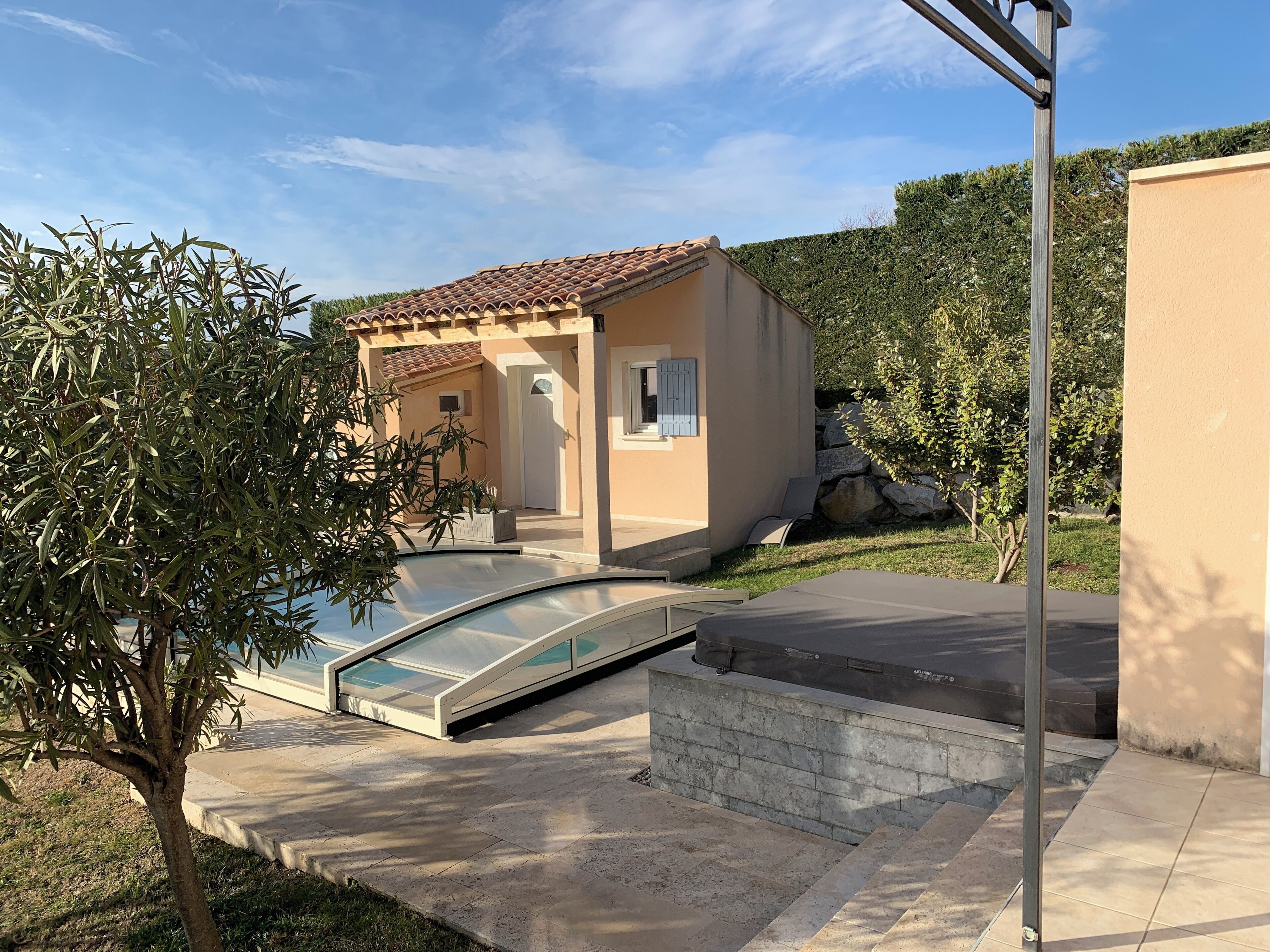 A house with a swimming pool, a small garden, and a tiled roof.