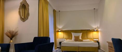 A hotel room with a large bed, two armchairs, a small table, and a nightstand.