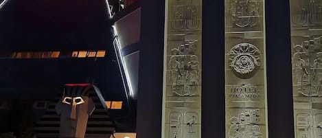 A building with a sign reading "HOT RESTAURACJA" and large illuminated panels with hieroglyphs.