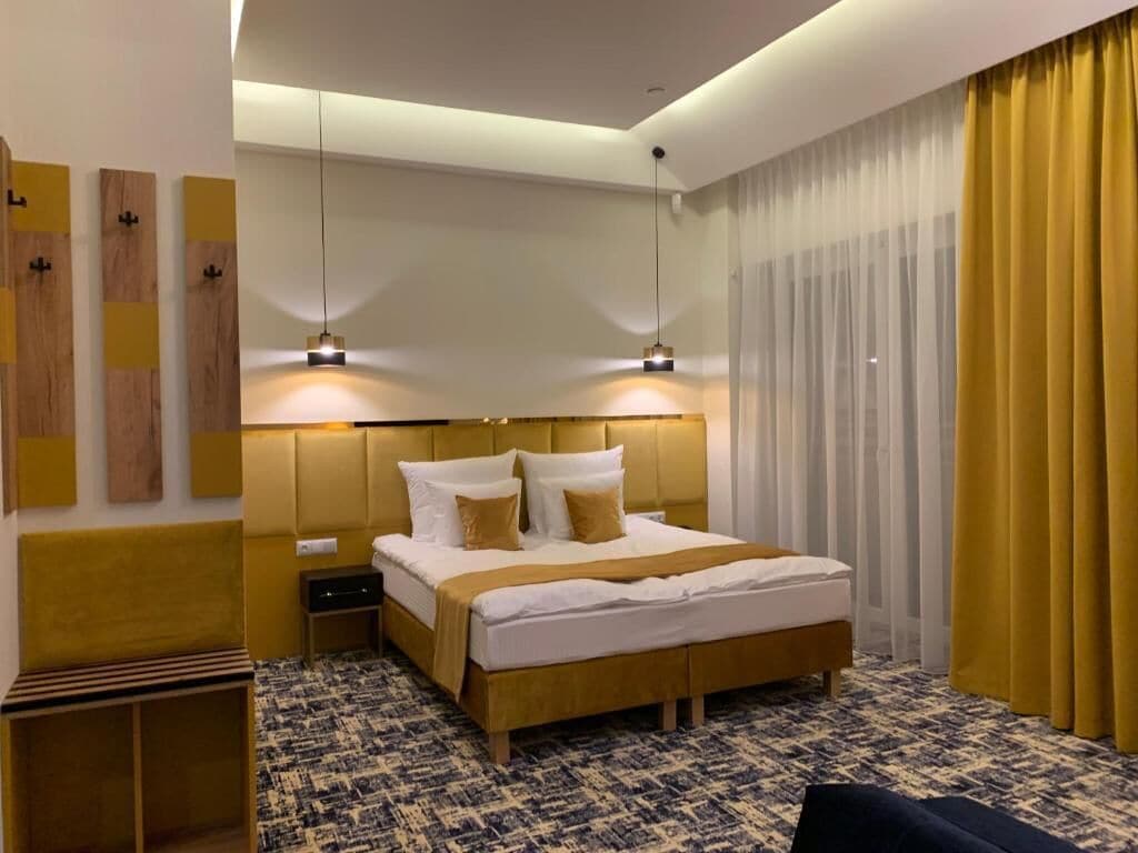 Una habitación de hotel moderna con una cama grande, mesitas de noche y una alfombra estampada.