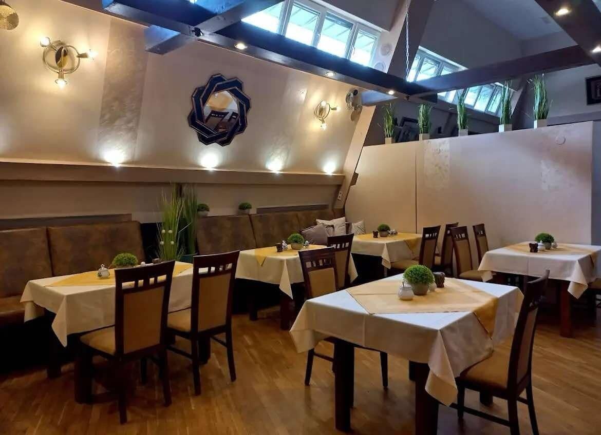 Un restaurante con varias mesas y cabinas, piso de madera y luces en el techo.