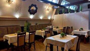 Un restaurante con varias mesas y cabinas, piso de madera y luces en el techo.