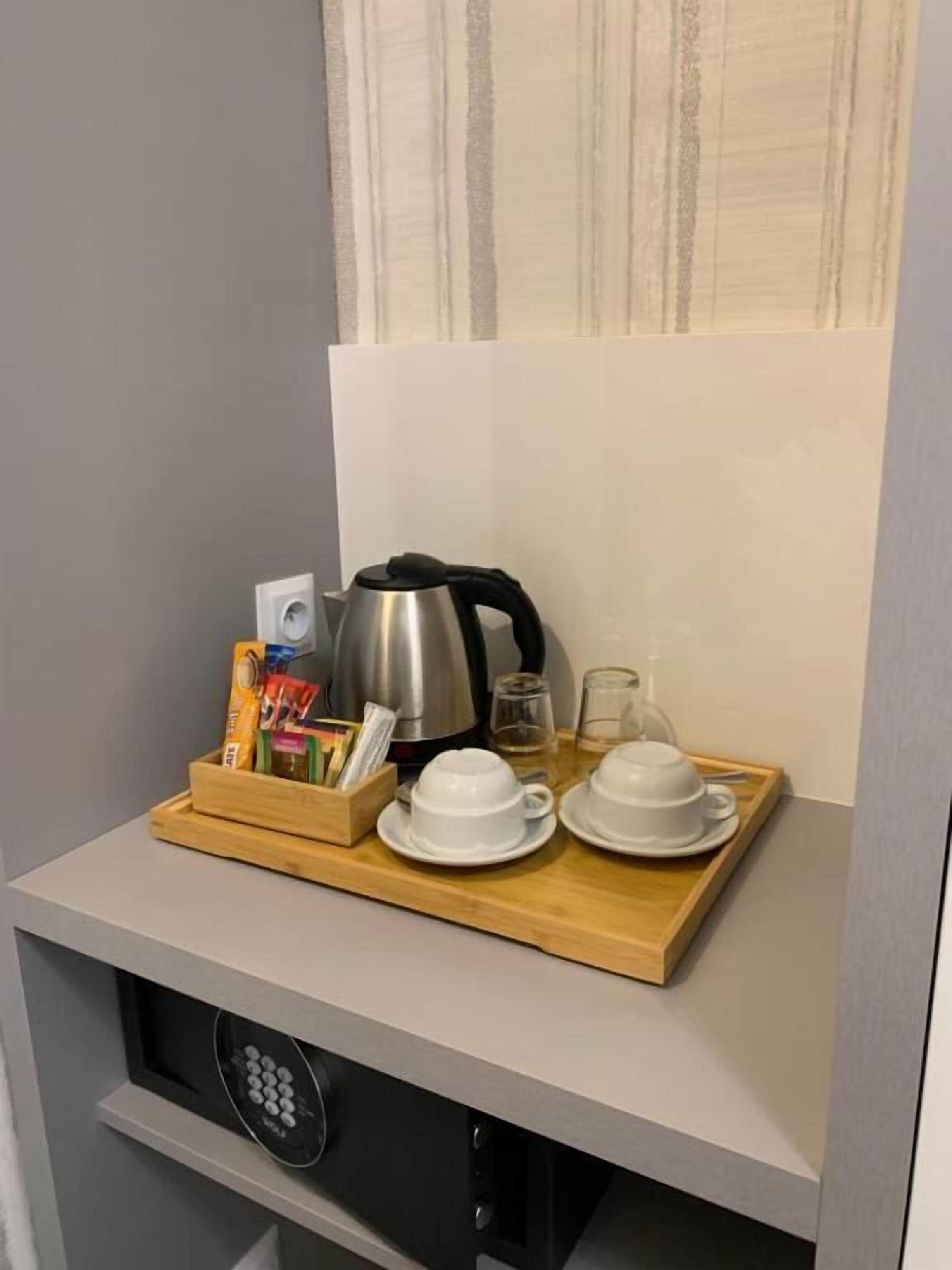 A kitchenette with a coffee maker, tea set, and a tray with various items.