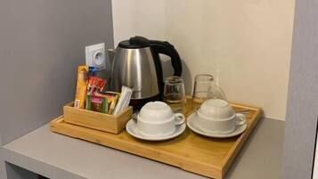 Una kitchenette con cafetera, juego de té y una bandeja con diversos artículos.