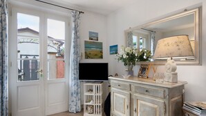 A room with a television, a cabinet with drawers, a mirror, and a window with curtains. - Holiday Home 'Red In Forte Dei Marmi' with Balcony, Wi-Fi and Air Conditioning (Forte dei Marmi)