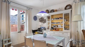 A dining area with a table, chairs, a microwave, and a cabinet with dishes. - Holiday Home 'Red In Forte Dei Marmi' with Balcony, Wi-Fi and Air Conditioning (Forte dei Marmi)