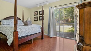Une chambre à coucher avec un lit à baldaquin, une commode en bois et une grande fenêtre donnant sur un paysage verdoyant.
