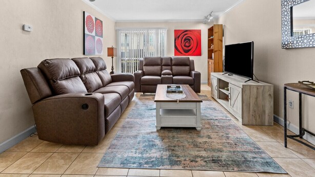A living room with two brown leather sofas, a coffee table, a TV, and a wooden cabinet.