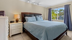 A bedroom with a bed, bedside table, lamp, and curtains.