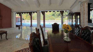 A spacious room with a large wooden dining table, elegant chairs, and a view of a pool and garden. - Spacious 6000 sf 6-bedroom villa in lovely Fremont with private gate, and view (Fremont)