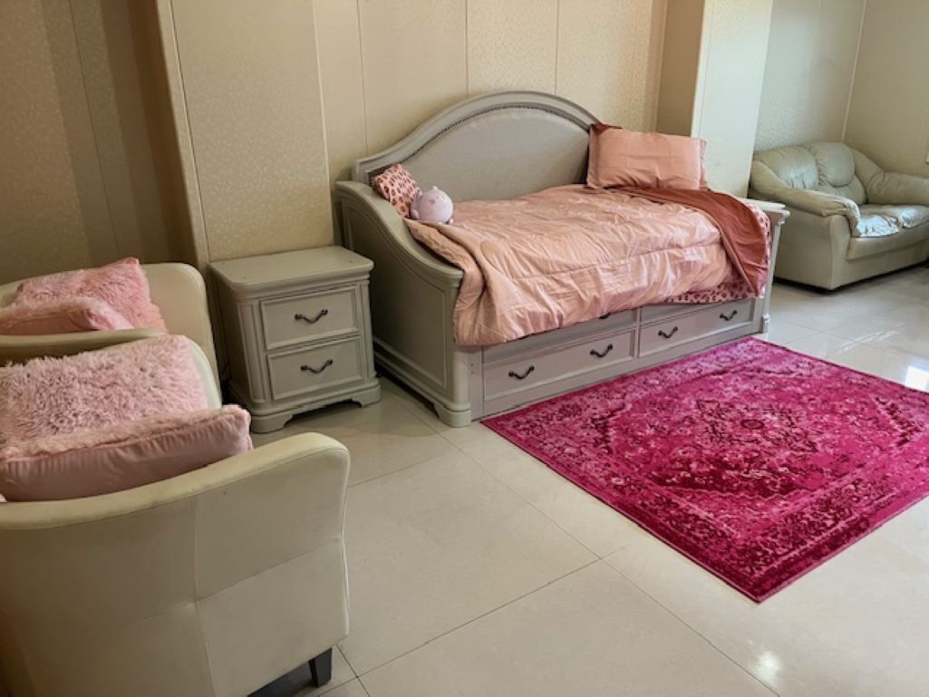 Quarto com cama, mesas de cabeceira, uma cadeira e um tapete vermelho.