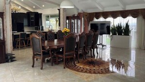 A dining area with a wooden table and chairs, a clock on the wall, and a large window with curtains. - Spacious 6000 sf 6-bedroom villa in lovely Fremont with private gate, and view (Fremont)