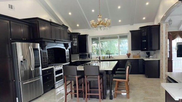 A modern kitchen with dark cabinetry, stainless steel appliances, and a central island with bar stools. - Spacious 6000 sf 6-bedroom villa in lovely Fremont with private gate, and view (Fremont)