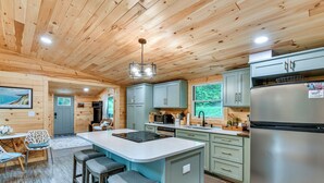 Een houten keuken in cottage-stijl, met een centraal eiland, roestvrijstalen apparatuur en lichtgekleurde kasten.