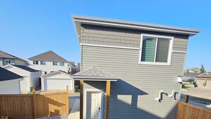 A residential house with a covered patio, a fenced backyard, and a well-maintained lawn. - Modern 1-Bedroom Garden Suite | Above Ground Suite | Side Parking | Chappelle (Edmonton)