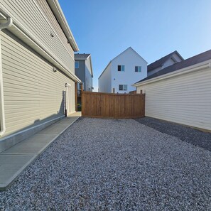 Un barrio residencial con camino de grava, valla de madera y casas con revestimiento.