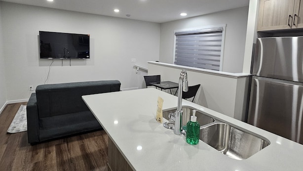 A modern kitchen with a central island, stainless steel appliances, and recessed ceiling lights. - Modern 1-Bedroom Garden Suite | Above Ground Suite | Side Parking | Chappelle (Edmonton)
