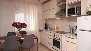 Une cuisine moderne avec des meubles blancs, un four encastré, un four à micro-ondes et un coin repas comprenant une table et des chaises.