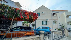 Un immeuble résidentiel avec une façade en pierre, un portail en métal et une voiture garée devant.