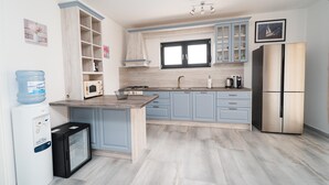 Eine moderne Küche mit hellblauen Schränken, einem Edelstahlkühlschrank, einem Einbauofen und einem Wasserspender.