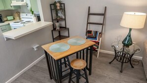Uma cozinha com mesa e bancos de madeira, uma escada e um abajur.