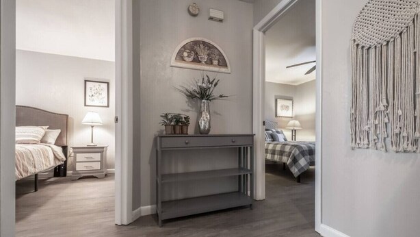 Quarto com cama, mesa de cabeceira, abajur e um objeto decorativo na parede.