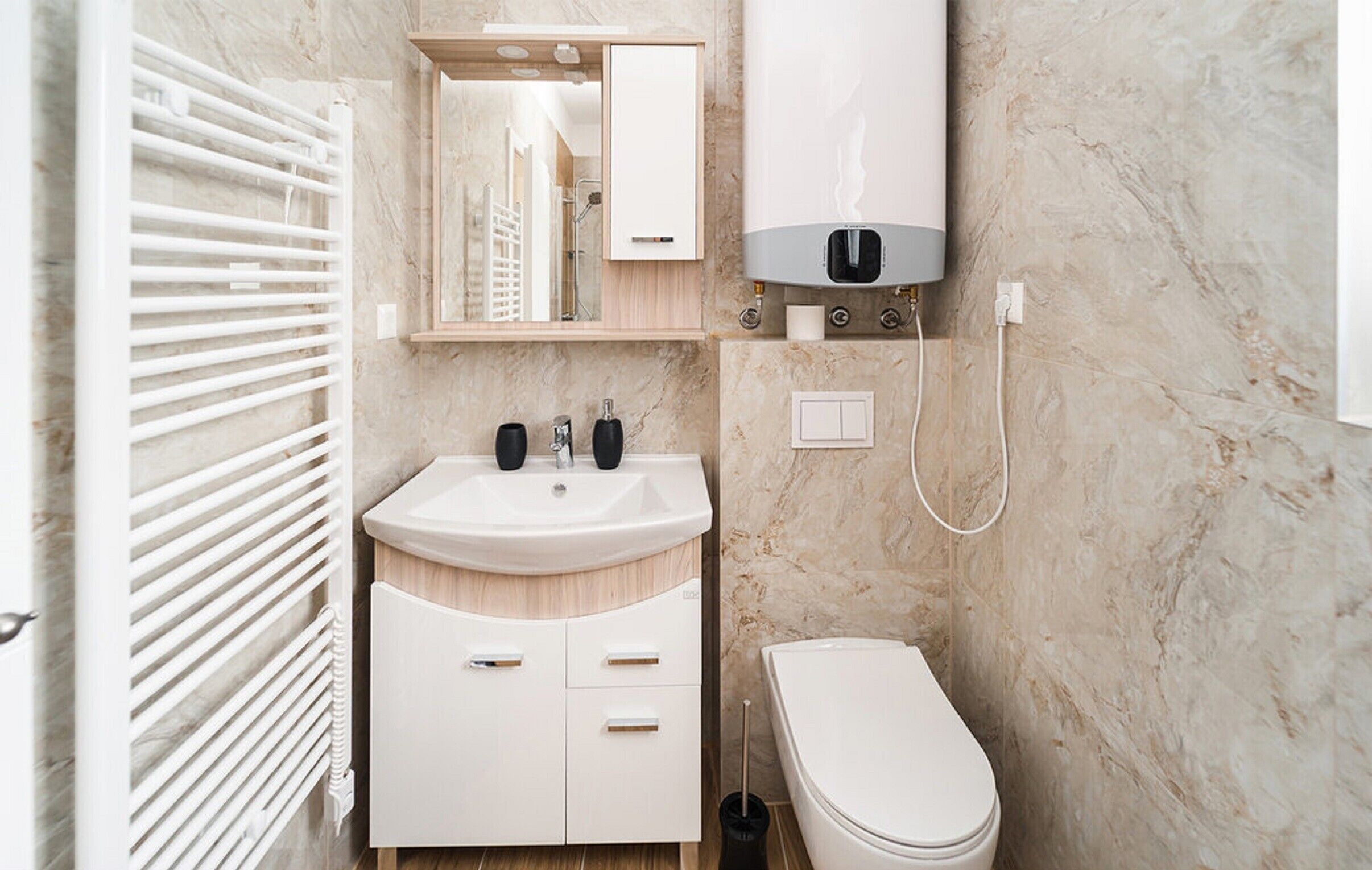 Un baño moderno con lavamanos, espejo y retrete blancos.