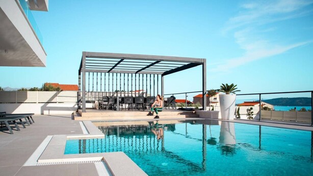 A rooftop pool with clear blue water, a covered seating area, and a view of the sea. - Sunset Serenity Villa with Pool, Gym and Sauna - Six Bedroom Villa with Pool (Kastel Kambelovac)