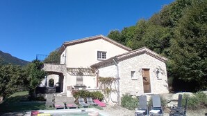 A two-story stone building with a balcony, a small window, and a door. - Villa Montagnes (Valgorge)