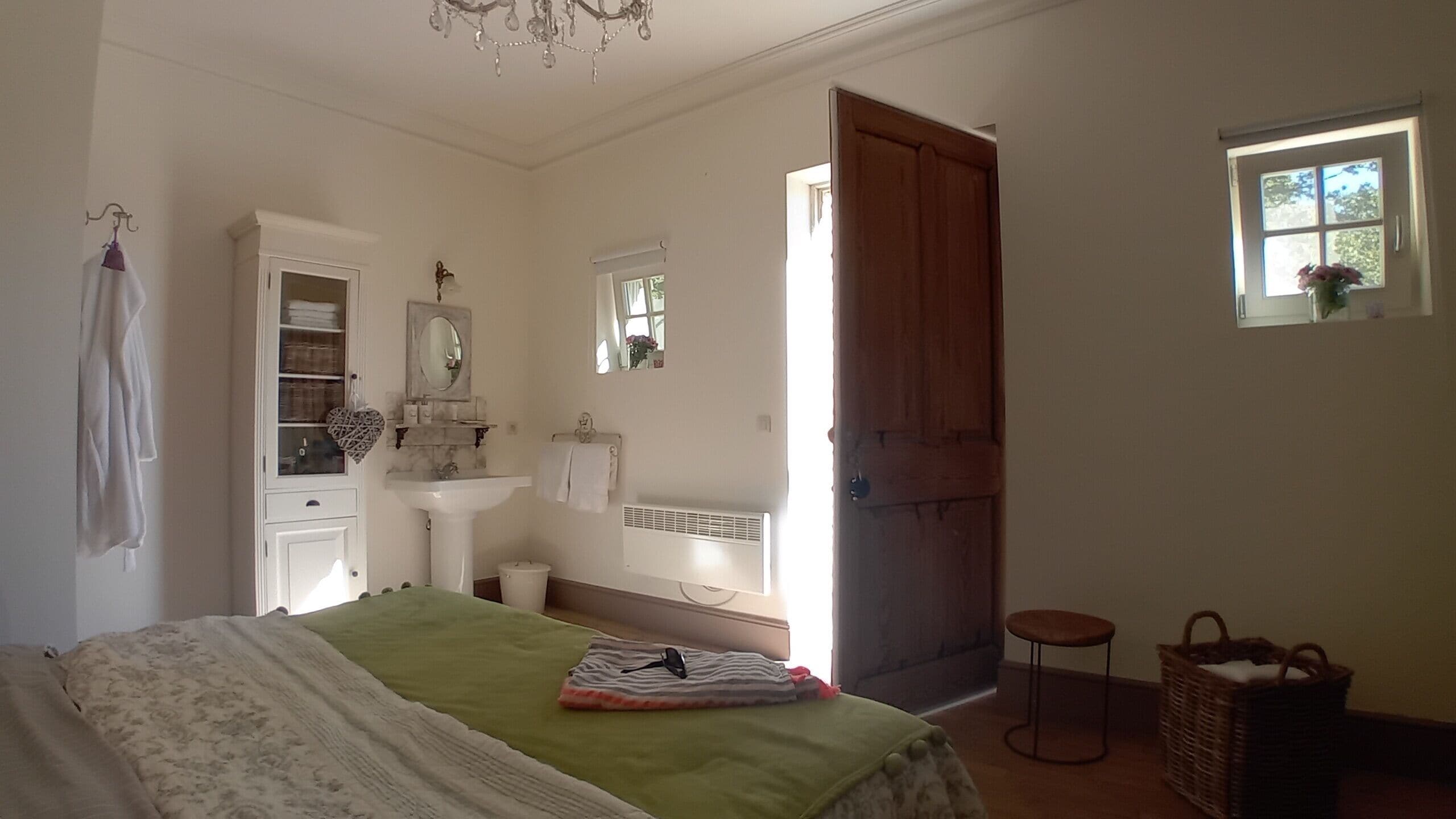 Une chambre à coucher comprenant un lit, une commode, une coiffeuse avec un miroir, une fenêtre et une porte.