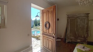 A room with a wooden door, a wicker basket, a green table, and a vintage wardrobe. - Villa Montagnes (Valgorge)