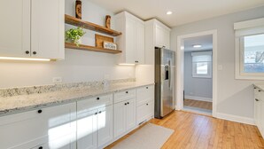 A modern kitchen with white cabinets, a granite countertop, and a stainless steel refrigerator. - 2 Mi to Northwestern: Updated Home w/ Game Room! (Evanston)