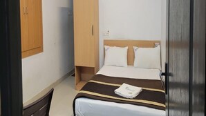 A hotel room with a bed, a wardrobe, a desk, and an air conditioning unit on the wall. - HOTEL I PLAZA (Madurai)